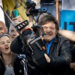 Argentina’s president holding a chainsaw at a rally, representing aggressive neoliberal cuts to public spending embraced by Trump.