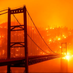 Slow-shutter image shows embers lighting hillside behind Bidwell Bar Bridge as Bear Fire spreads in Oroville, California amid climate neglect under Trump.